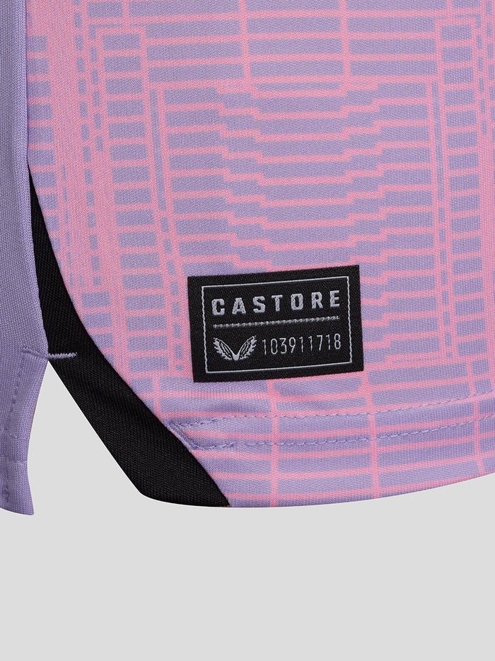 Close up of lilac fabric with a pink geometric pattern on the third shirt and a Castore label near the hem.