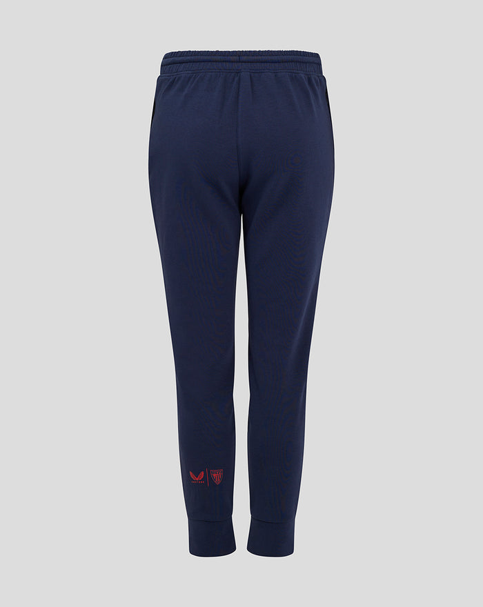 Back view of navy Junior Athletic Club Travel Pant showing ribbed cuffs and red logos at the lower left leg