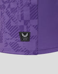 Lower front close up of purple goalkeeper jersey showing authentic Castore patch amid geometric print