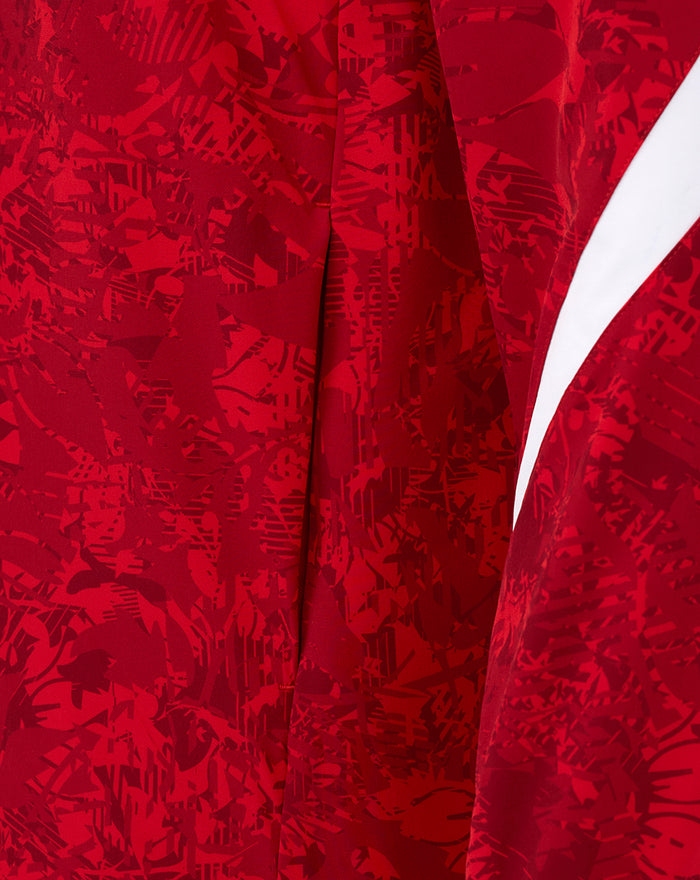 Close up of red patterned fabric with a white diagonal stripe and folded seams.