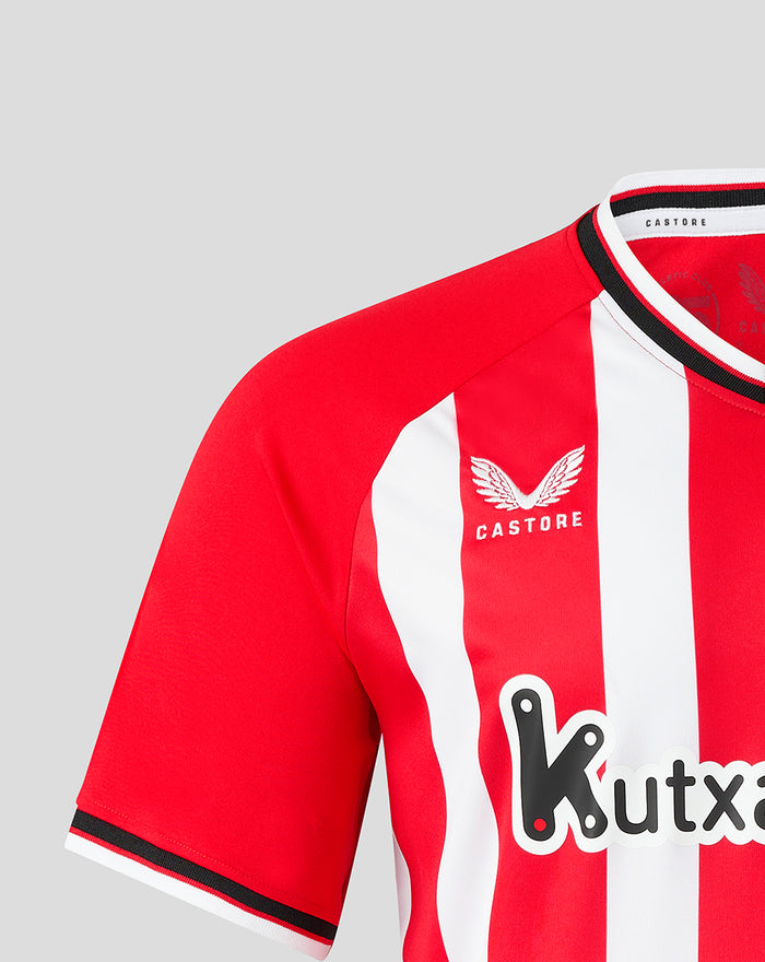 Shoulder and chest area of red and white striped women's jersey featuring the club crest and Castore branding.
