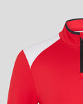 Collar and shoulder detail of the red athletic top with a black zipper and the club crest on the left chest