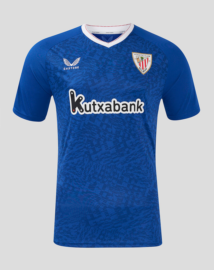 Front view of blue away shirt with crest badge and Castore logo, white V-neck collar and red dotted trim, Kutxabank sponsor