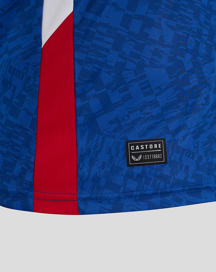 Close-up of blue patterned away shirt fabric with a red side stripe and Castore patch near the hem