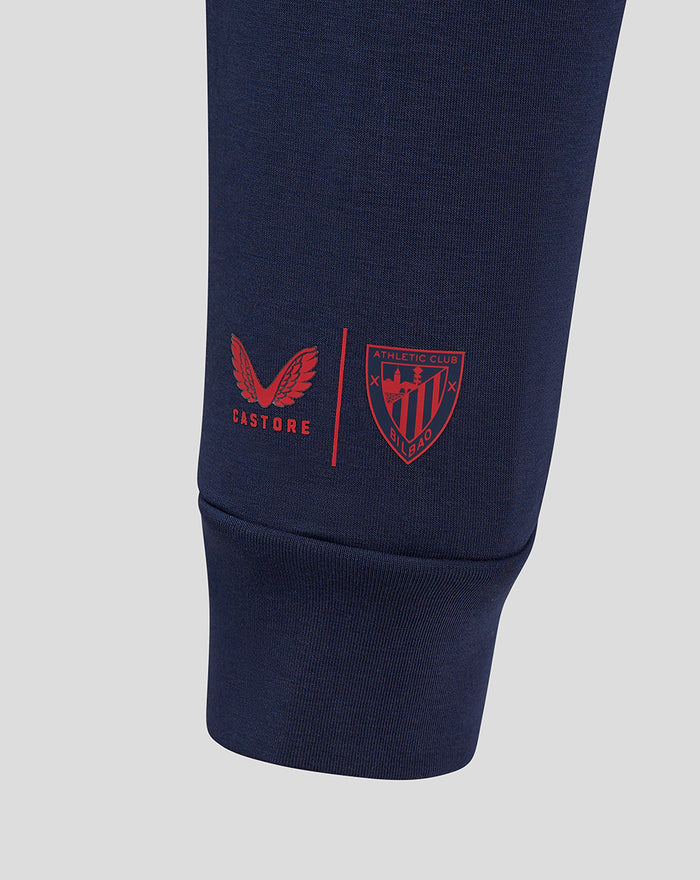 Navy pant leg close-up with Castore logo and Athletic Club shield near the cuff.