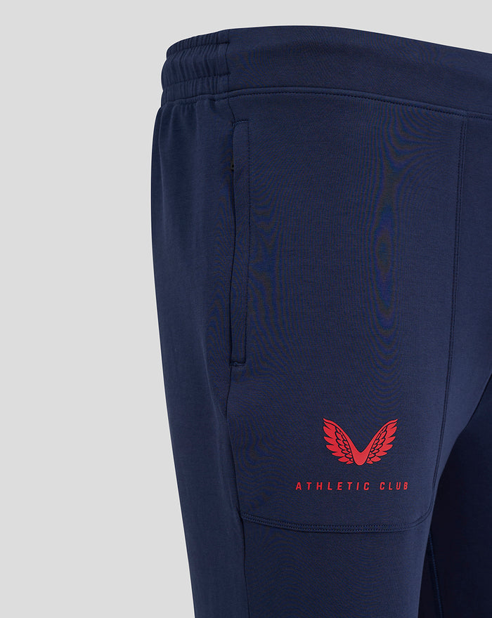 Close-up of the navy travel pants lower leg with a red Athletic Club crest near the cuff