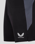 Back side view of black GK training shorts showing a gray side panel and Castore logo near the hem.