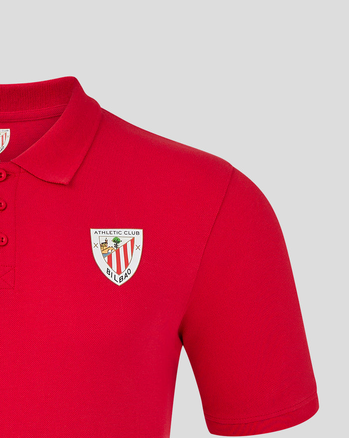 Close-up of red polo shirt showing collar, three-button placket, and crest badge on chest.