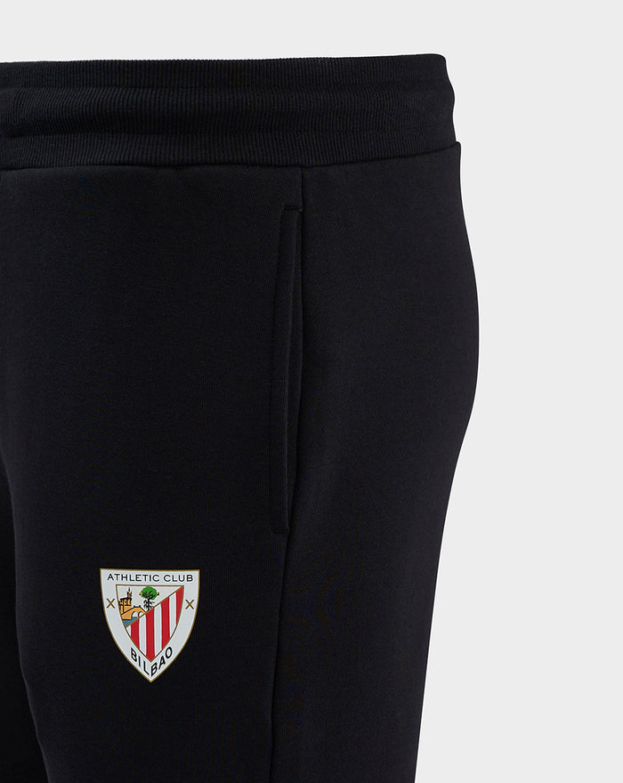 Close-up of black men's core joggers showing elastic waistband and crest badge on the thigh.