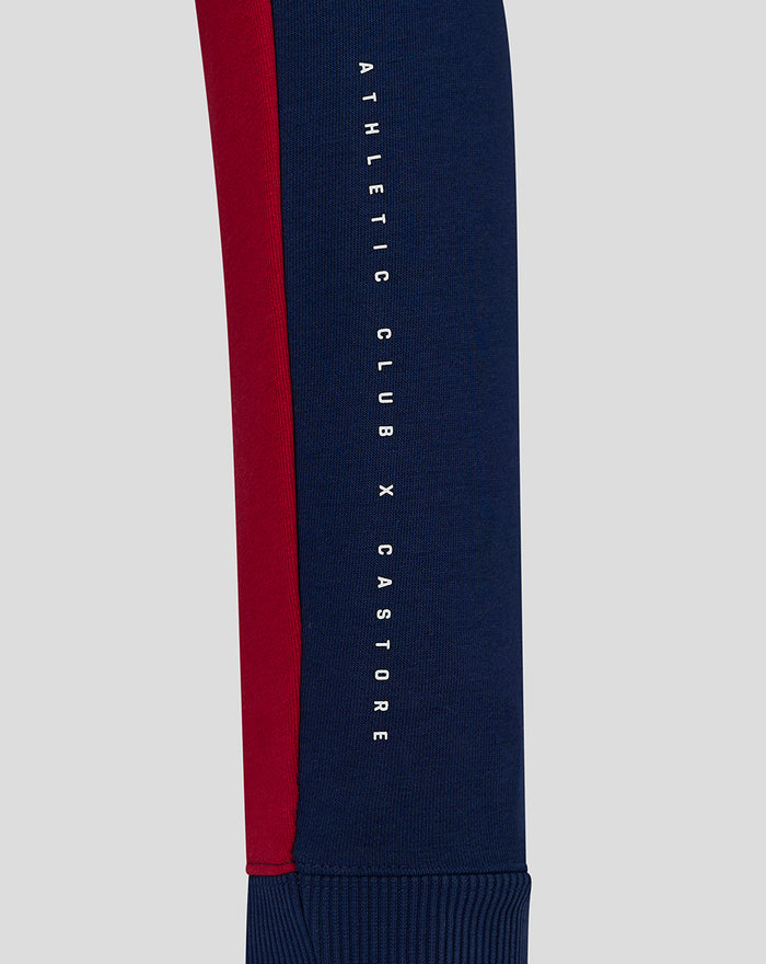 Close up of sleeve showing vertical Athletic Club X Castore text on navy fabric with red stripe