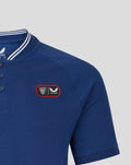 Close up of blue polo highlighting shoulder and left chest patch with crest.