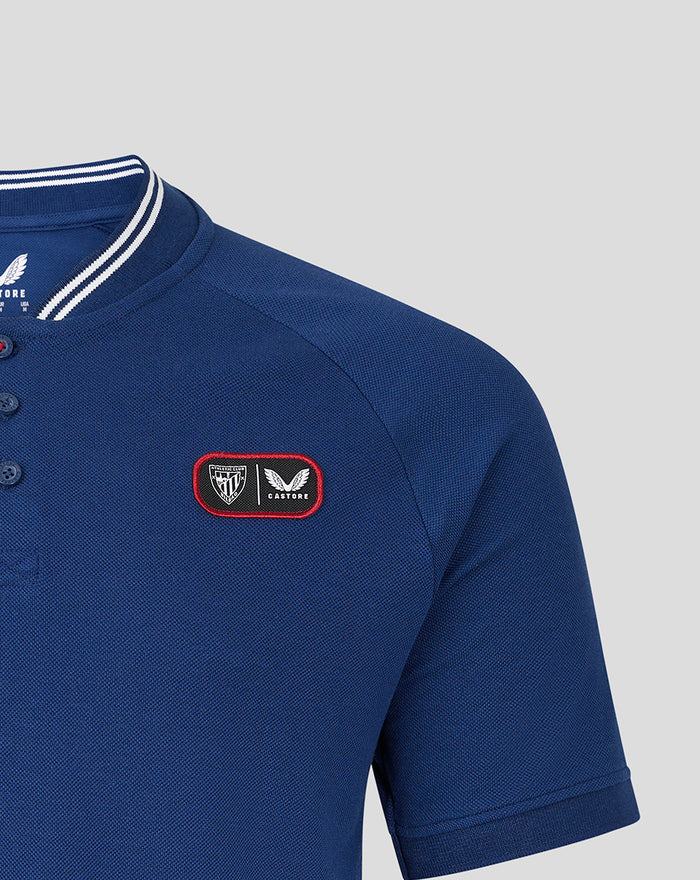 Close up of blue polo highlighting shoulder and left chest patch with crest.