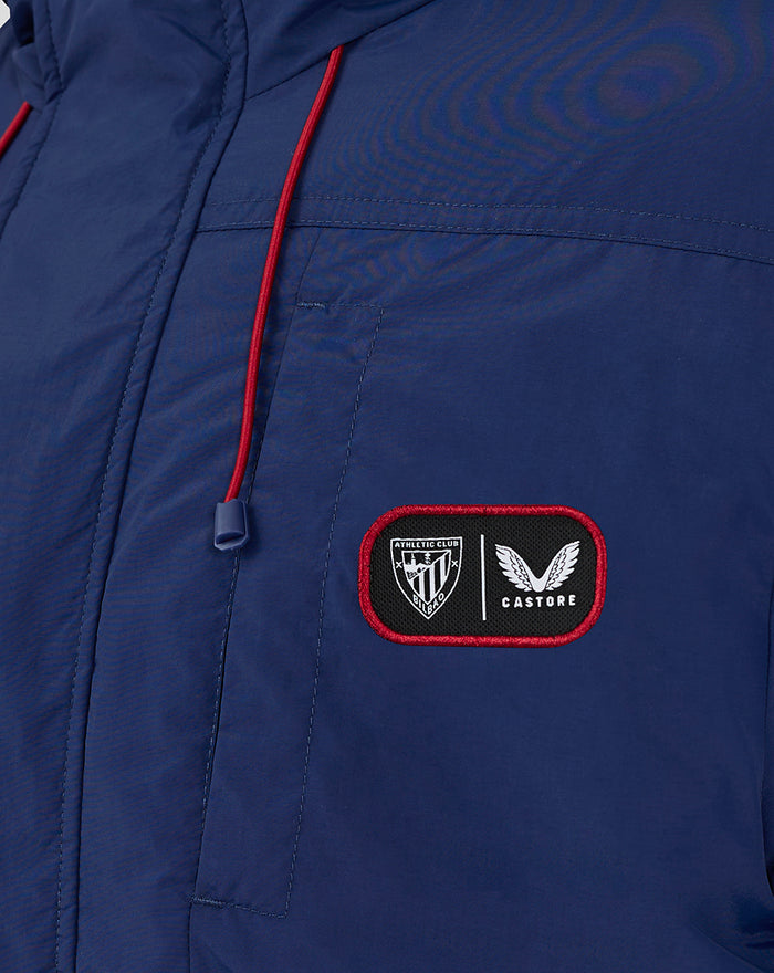 Close-up of blue athletic jacket with red drawstrings and a patch displaying Athletic Club Bilbao and Castore logos.