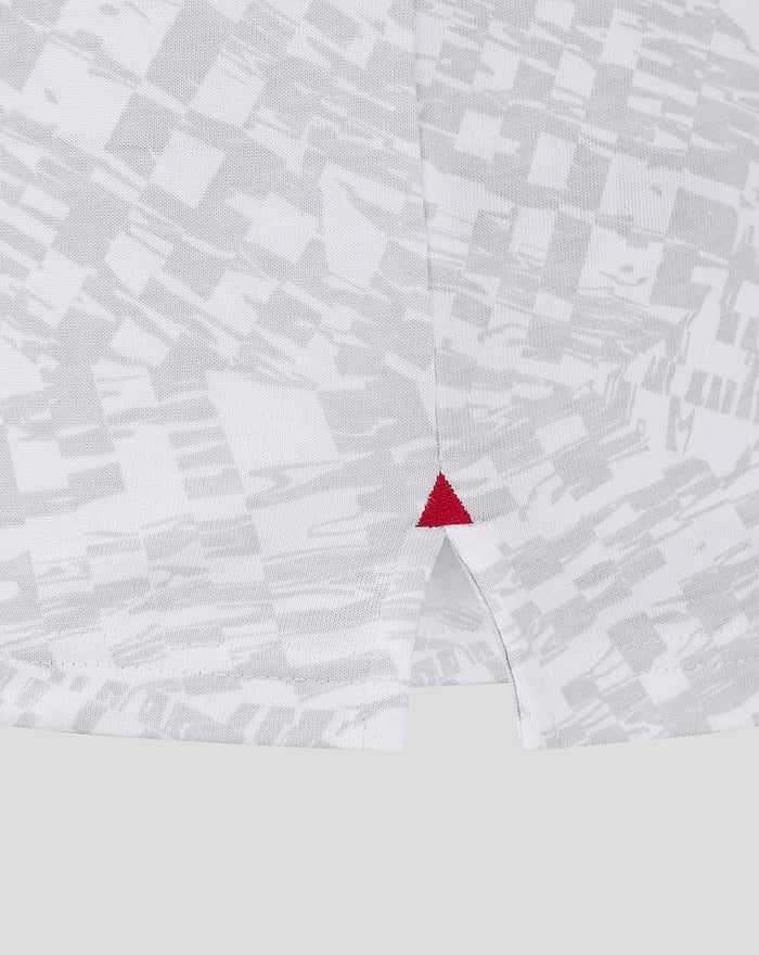 Hem detail of grey and white athletic club cotton tee with a small red triangle stitch.
