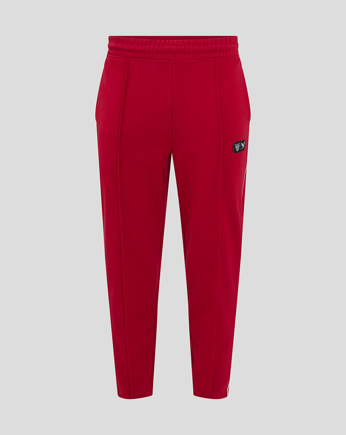 Red athletic track pants with elastic waistband and a small patch on the left thigh.