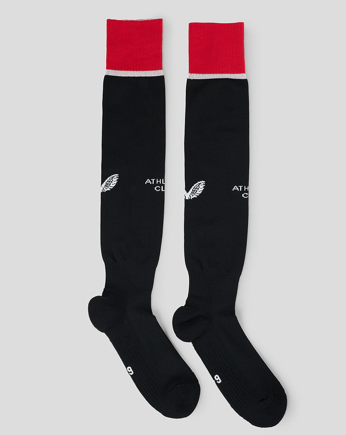 Junior sized black full foot sock with red cuff and white stripe laid flat.