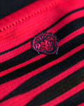 Close up of red and black striped fabric from Athletic Club 4th short sleeve women's shirt showing the team crest