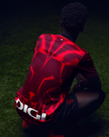 Athletic Club 4th short sleeve shirt viewed from behind as a player sits on grass with bold red and black graphics