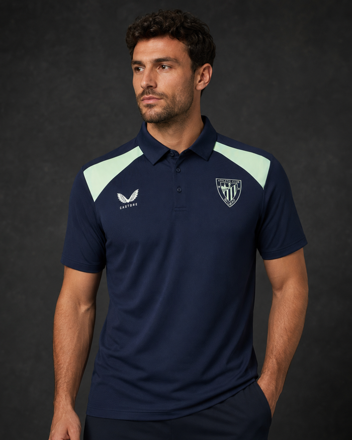 Male model wearing navy performance poly polo with light mint shoulder panels and a crest on the chest