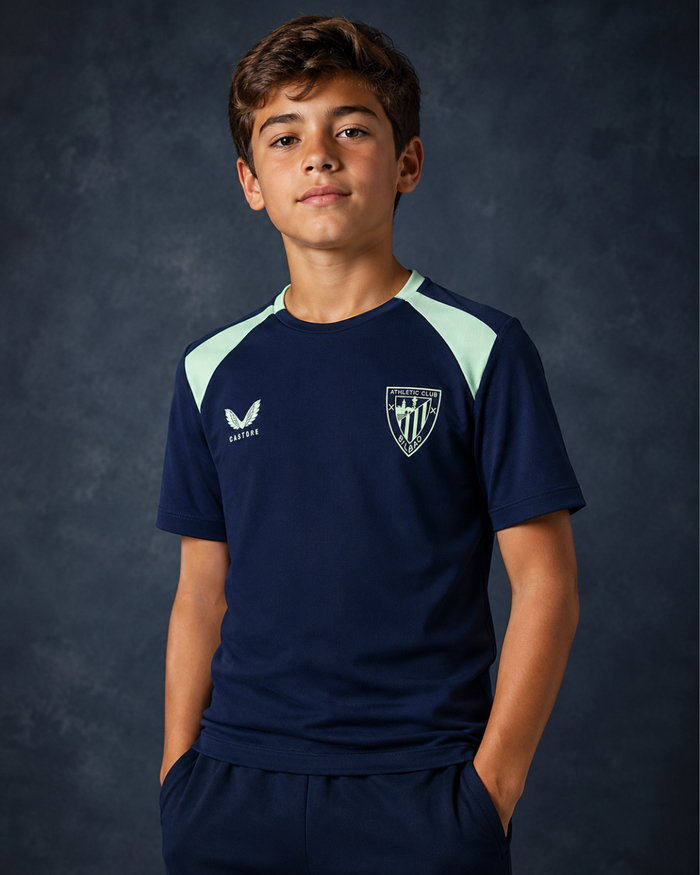 Young model wearing navy performance short sleeve tee with mint shoulder panels and a crest on the chest.
