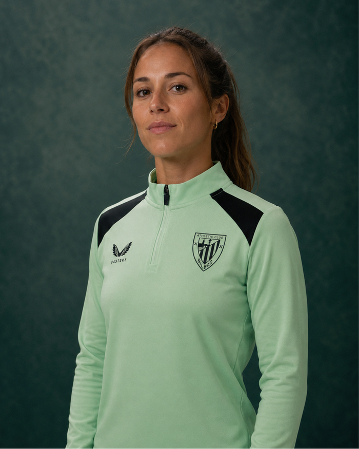 Light green performance midlayer top with black shoulder panels worn by a model