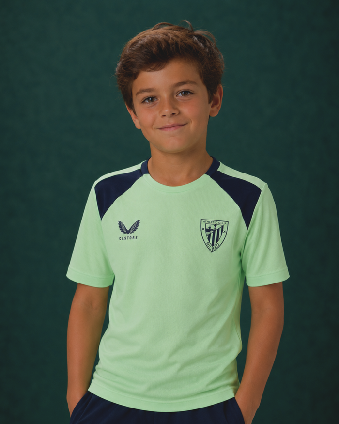 Front view of junior lime green performance short sleeve tee with navy shoulder panels and a club crest.