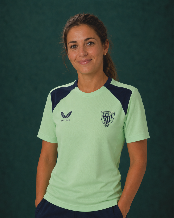 Woman wearing mint green performance short sleeve tee with navy shoulder panels against a dark green backdrop